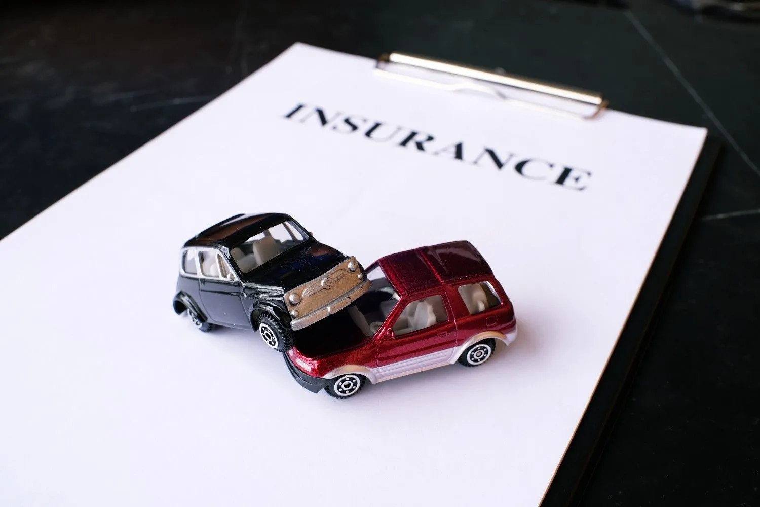 Two model cars after a bump, sitting on an insurance form