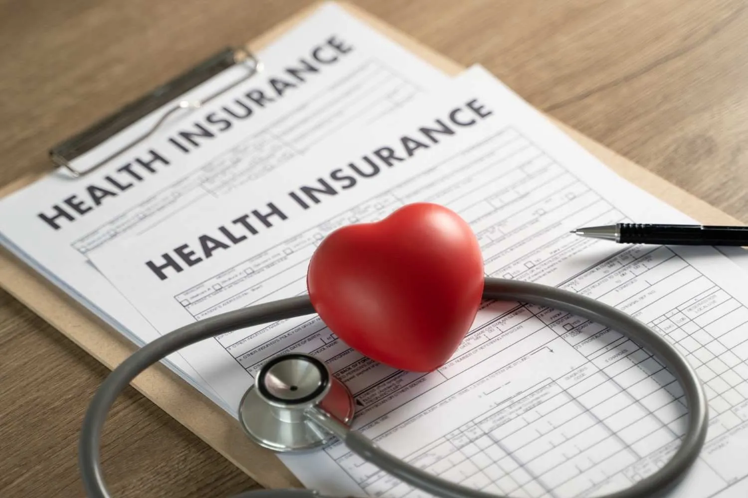 Health insurance forms on a clipboard with a stethoscope and a red heart