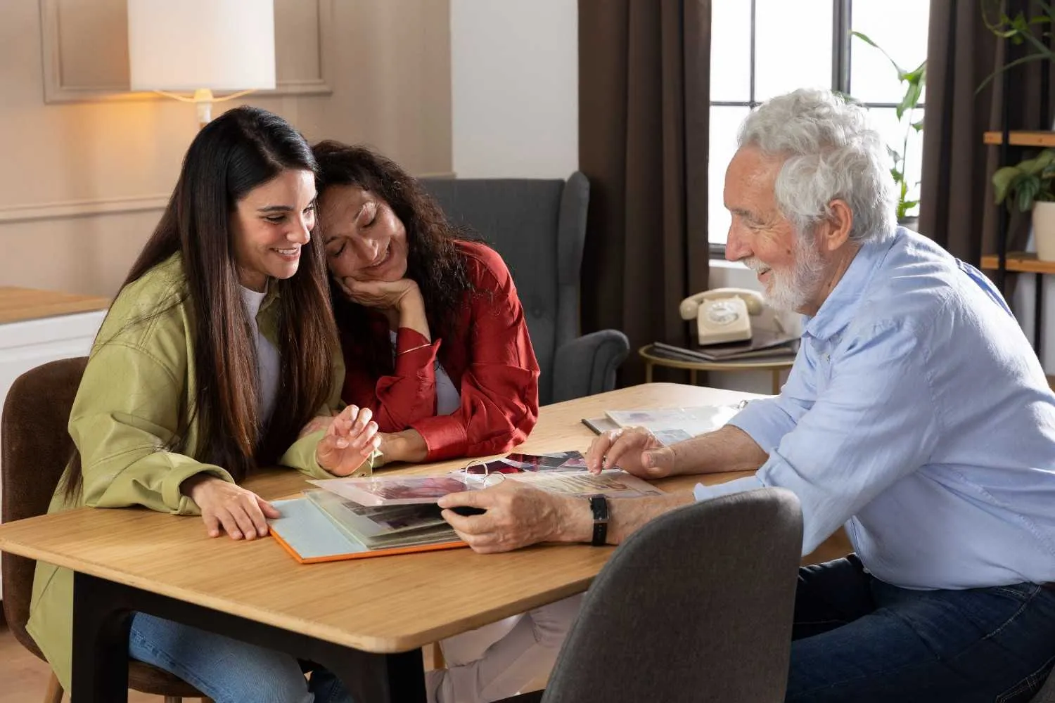 Three family members looking through photo albums together at a table